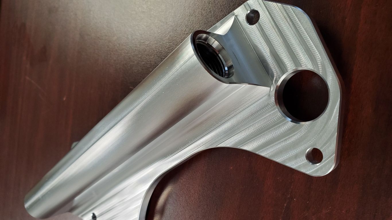 A machined metal part with a threaded opening and circular holes.