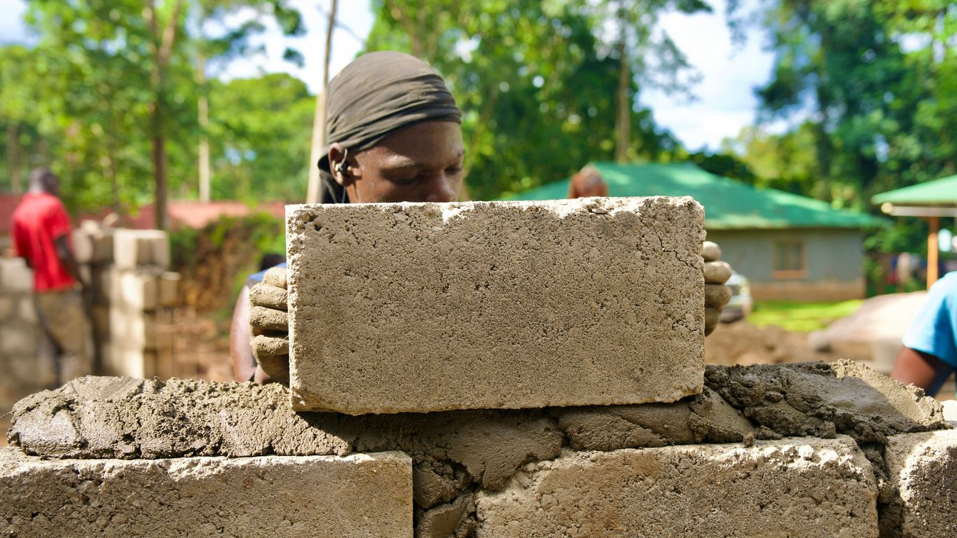 A person is building a wall with concrete blocks.