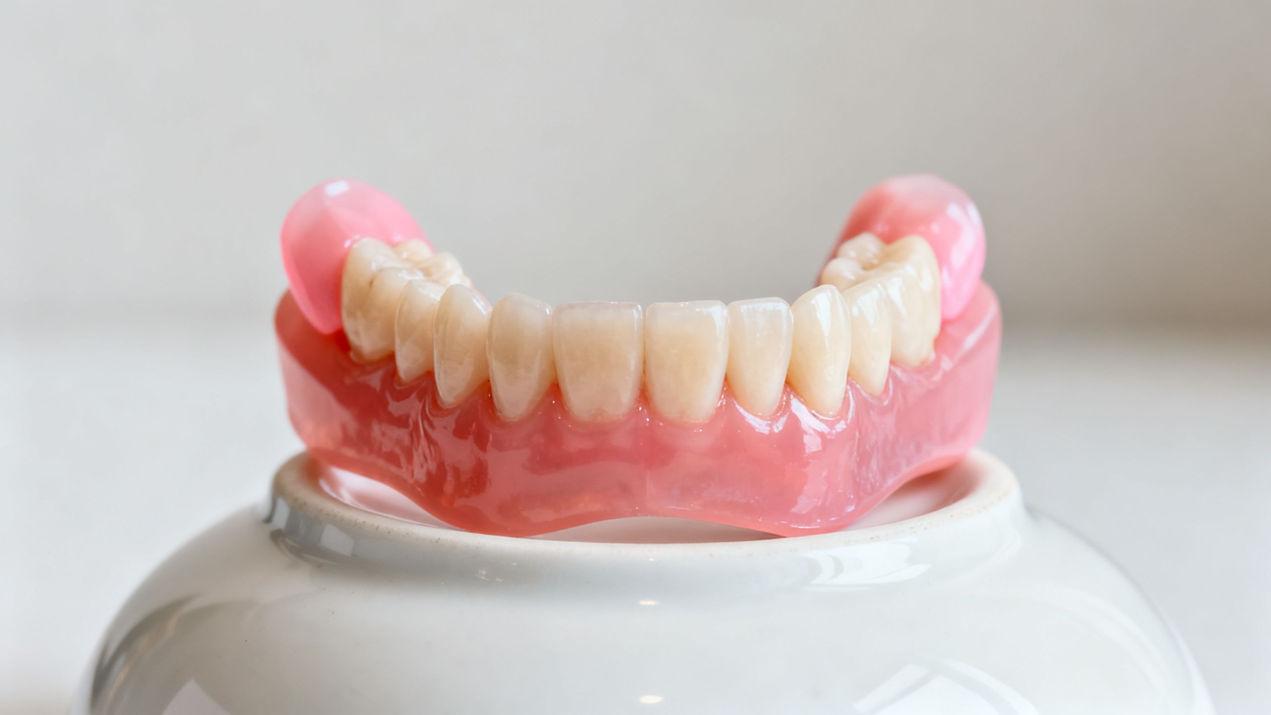 A full set of upper dentures resting on a white dish.