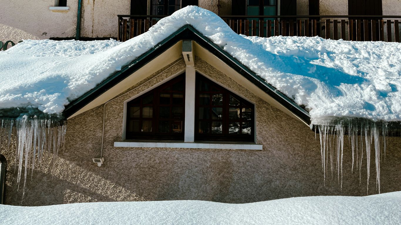 a house covered in snow with icicles hanging from the roof