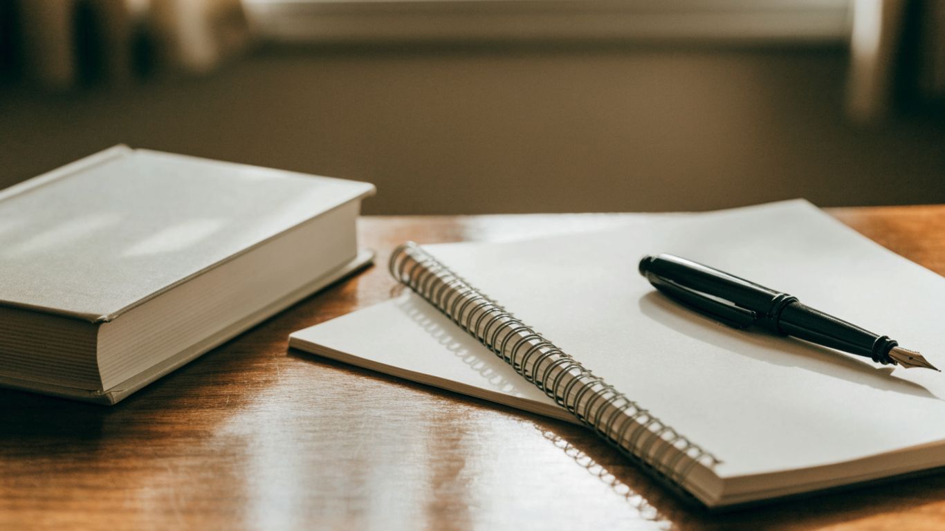 A poetry book and notebook on a wooden desk
