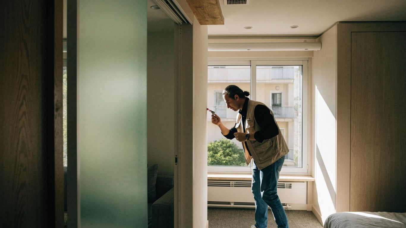 Bright apartment interior with a surveyor inspecting a wall