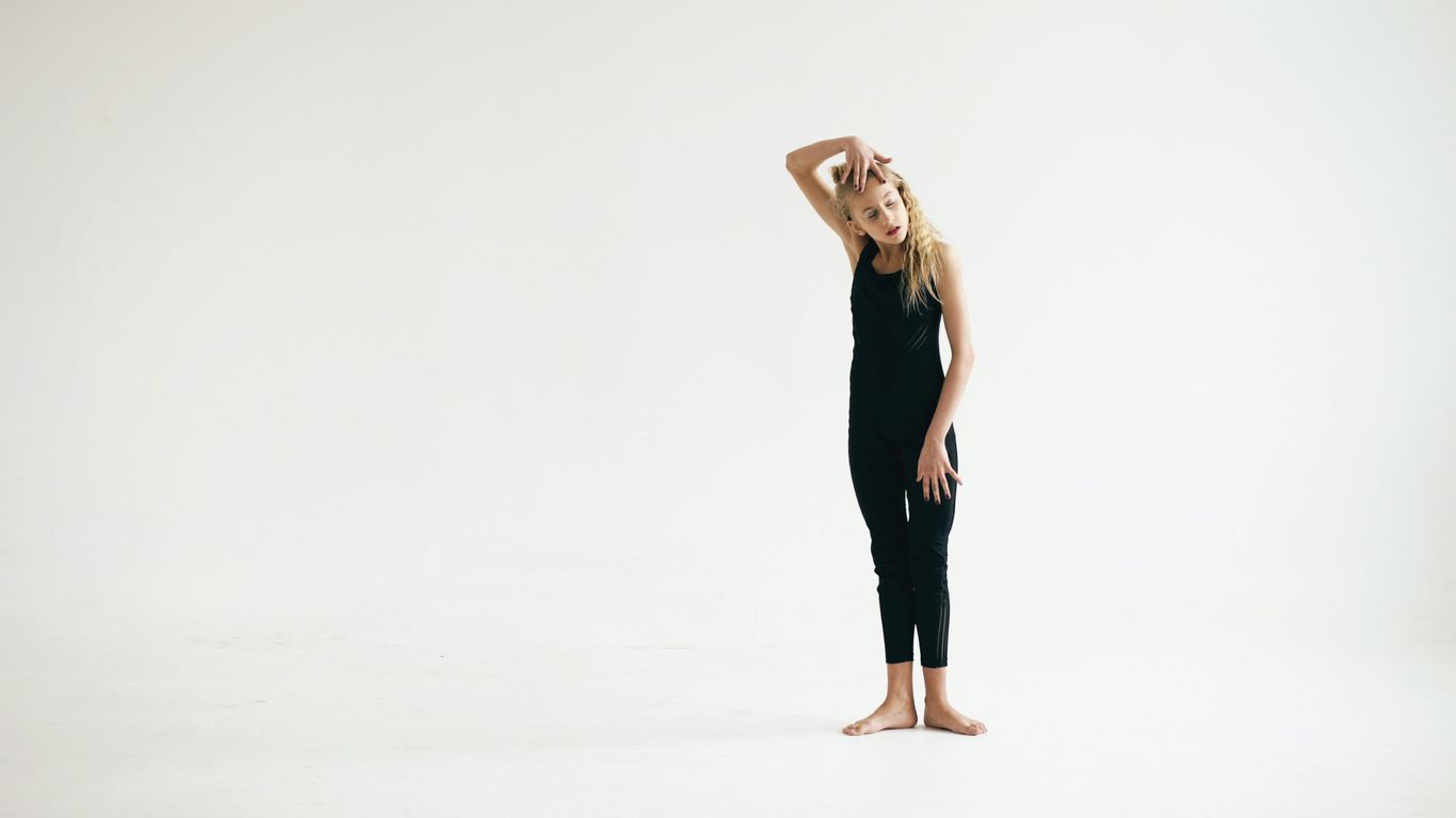 Young girl in black leotard on white background.