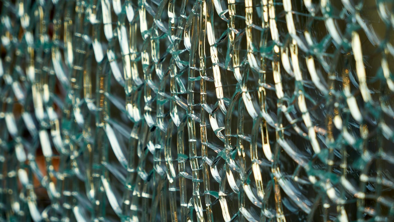 a close up of a metal fence with broken glass