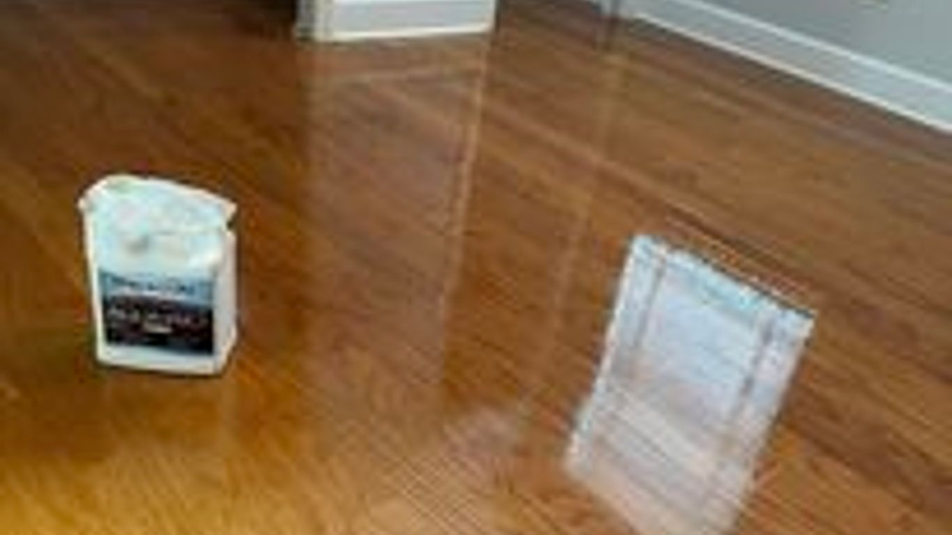 Shiny hardwood floor with a container of cleaning product.