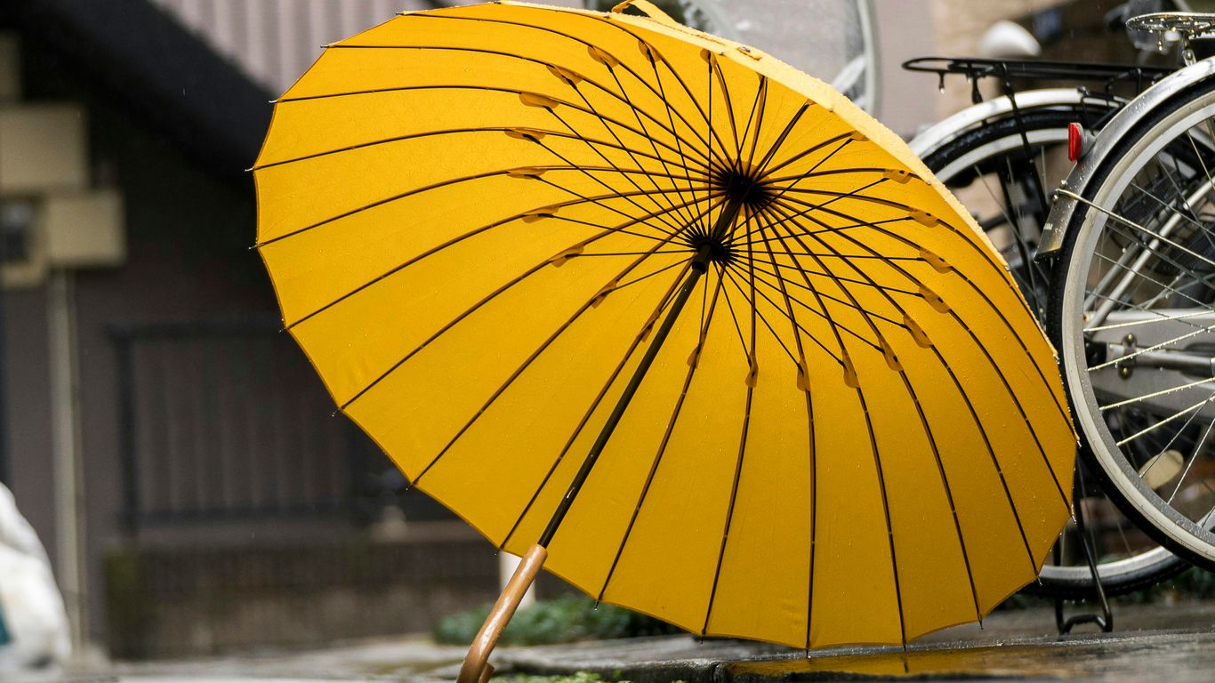 A bright yellow umbrella leaning on bicycles