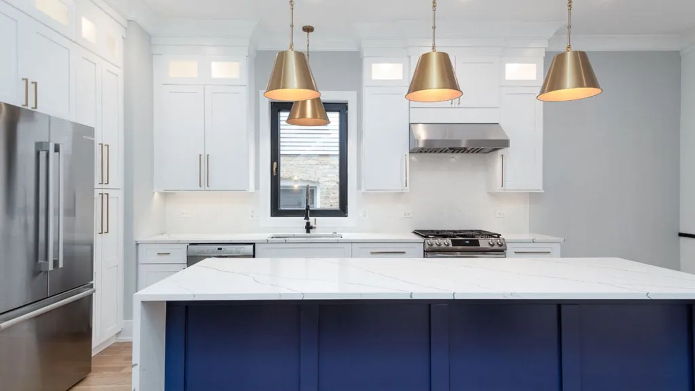 Modern kitchen with white cabinets, blue island, and stainless steel appliances.
