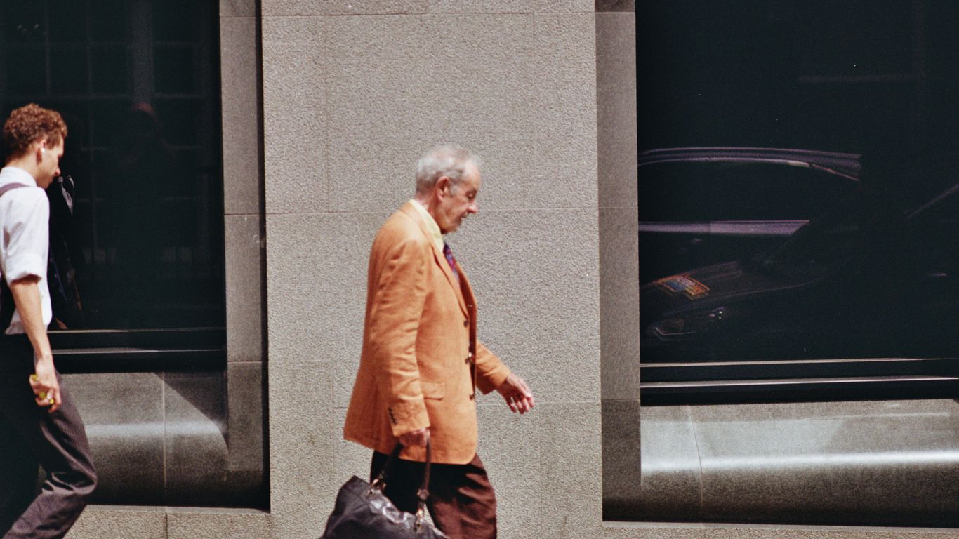An older man walks down a city street.