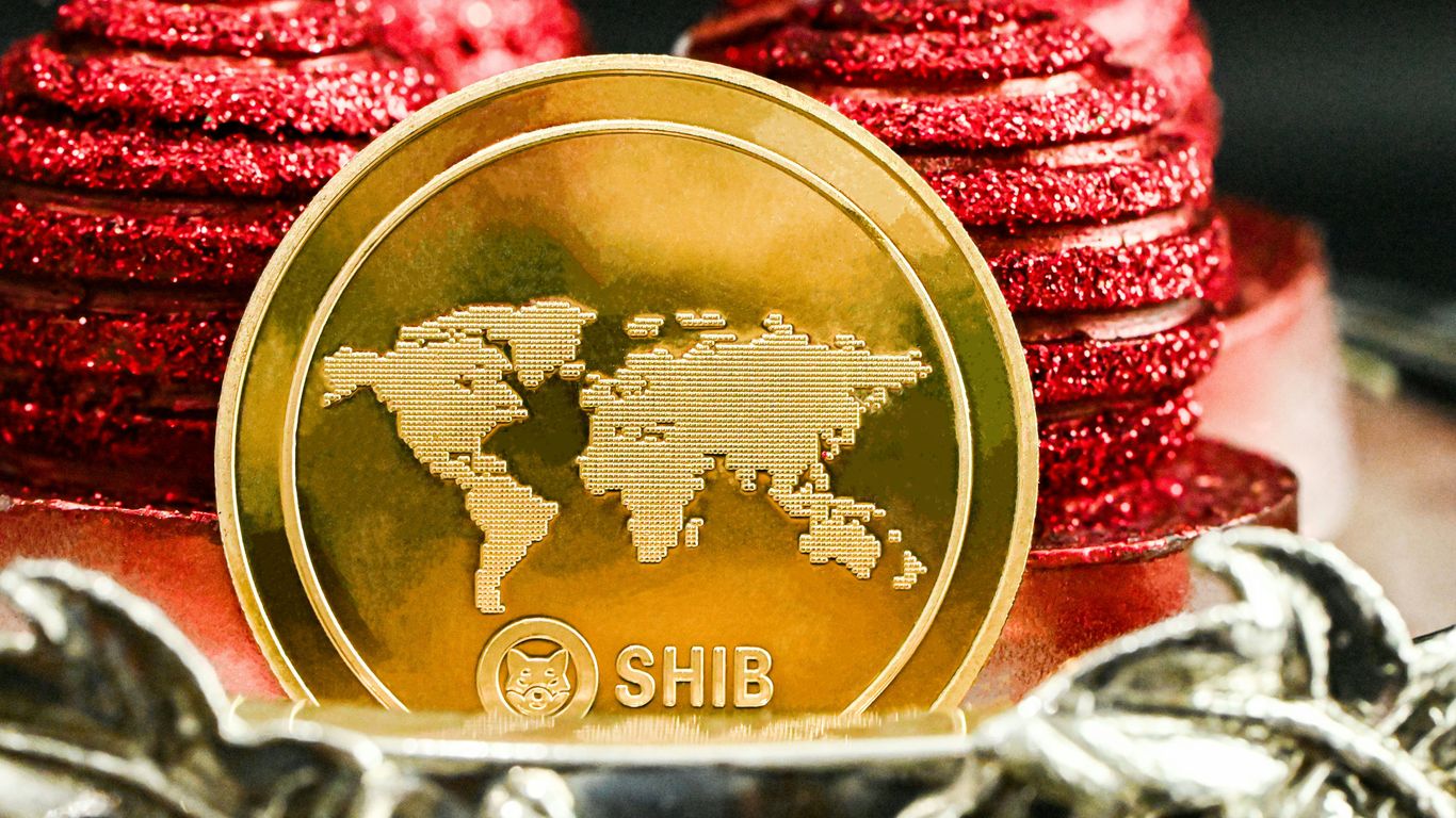 Gold coin with world map design and SHIB cryptocurrency logo.
