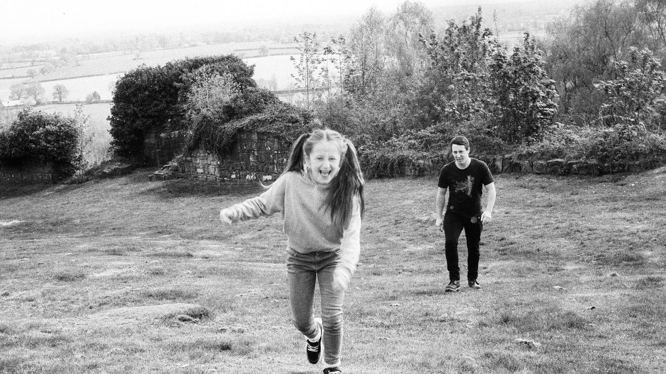 Girl running towards camera with man behind her