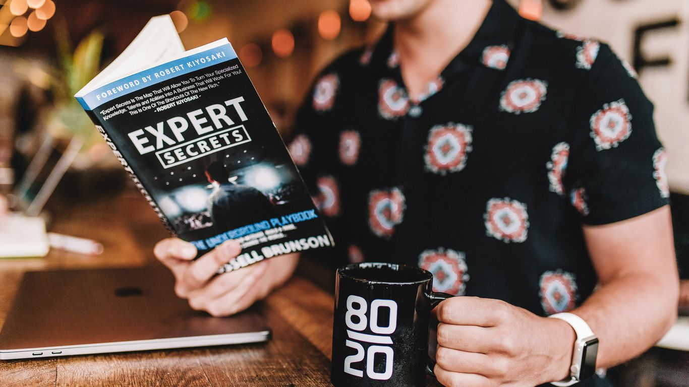 smiling man reading book while holding mug