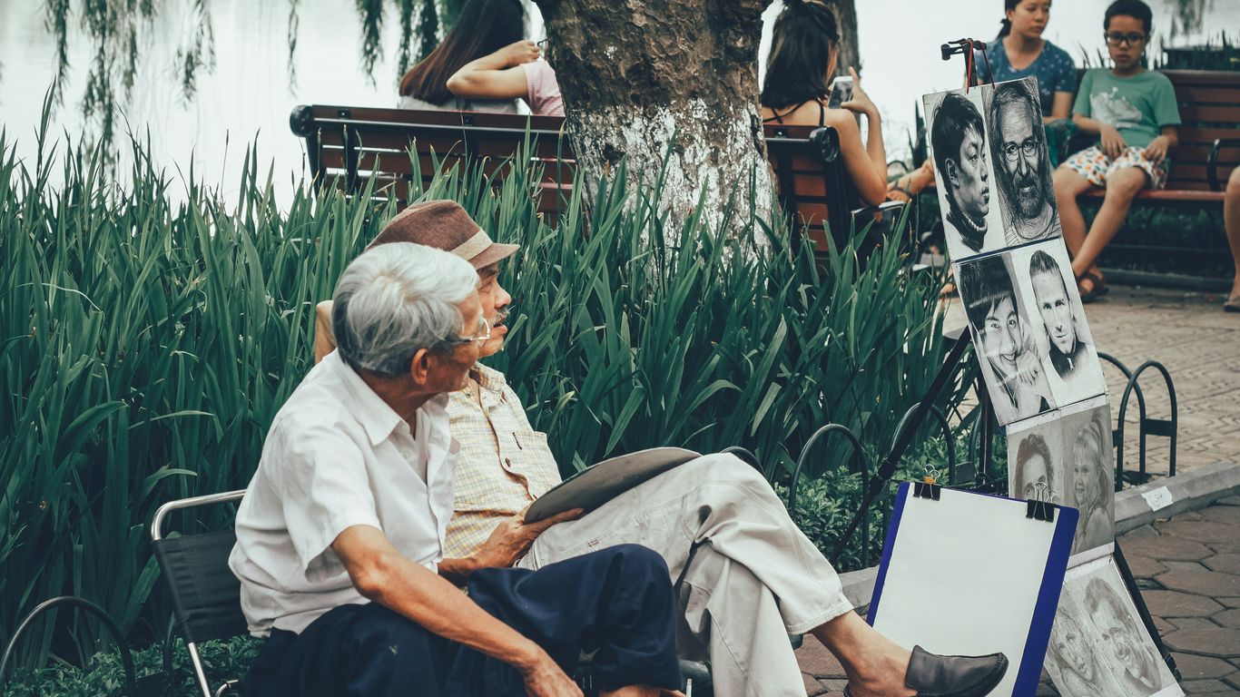 two men sitting on bench beside portrait paintings