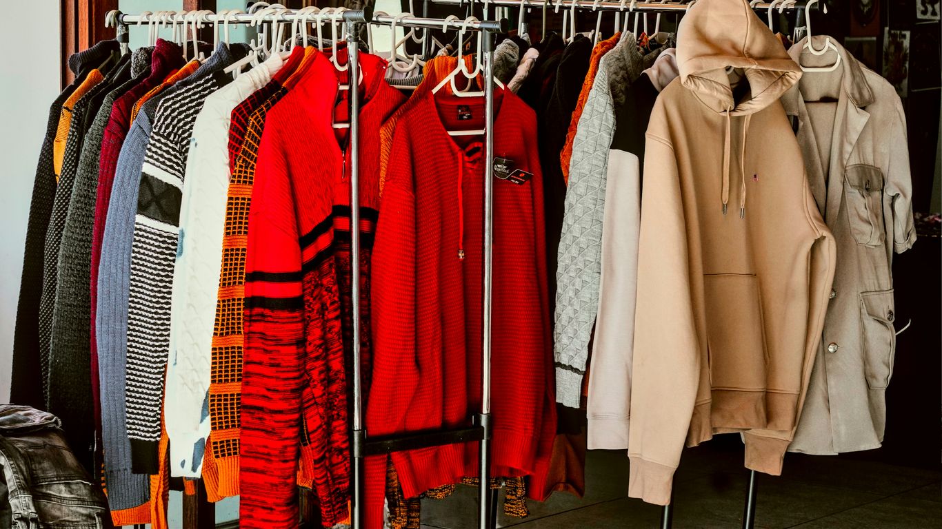 A rack of clothes in a closet with clothes hanging on it