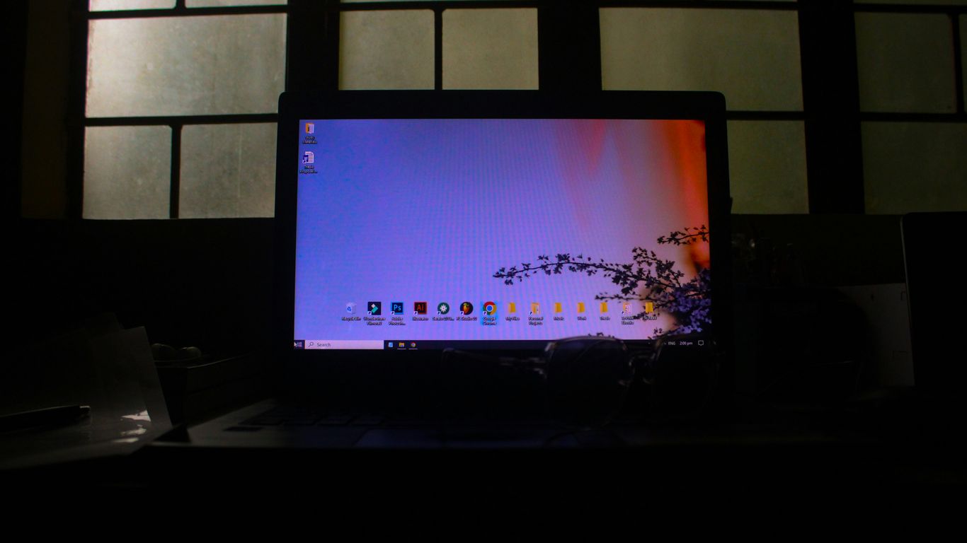 A laptop displaying a colorful desktop in a dark room.