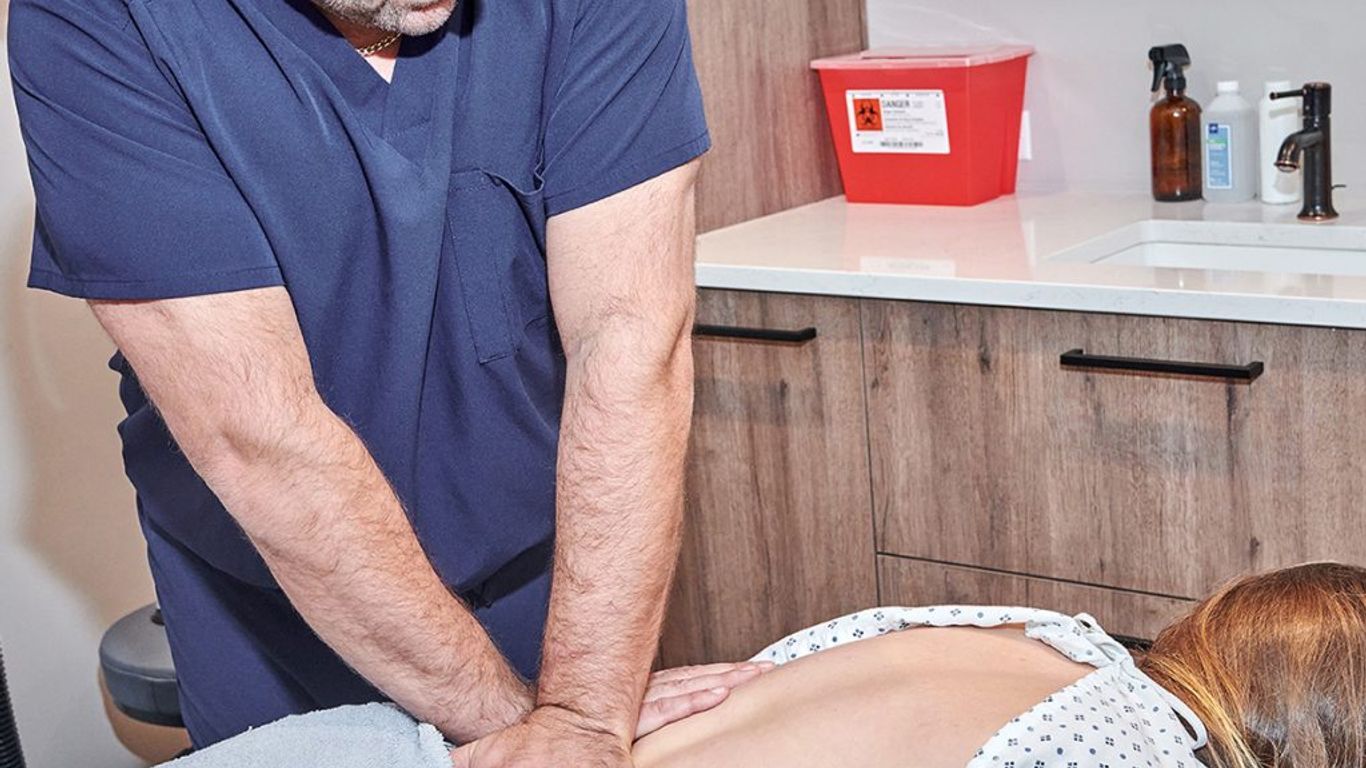 A person is receiving a massage on their back in a medical setting.