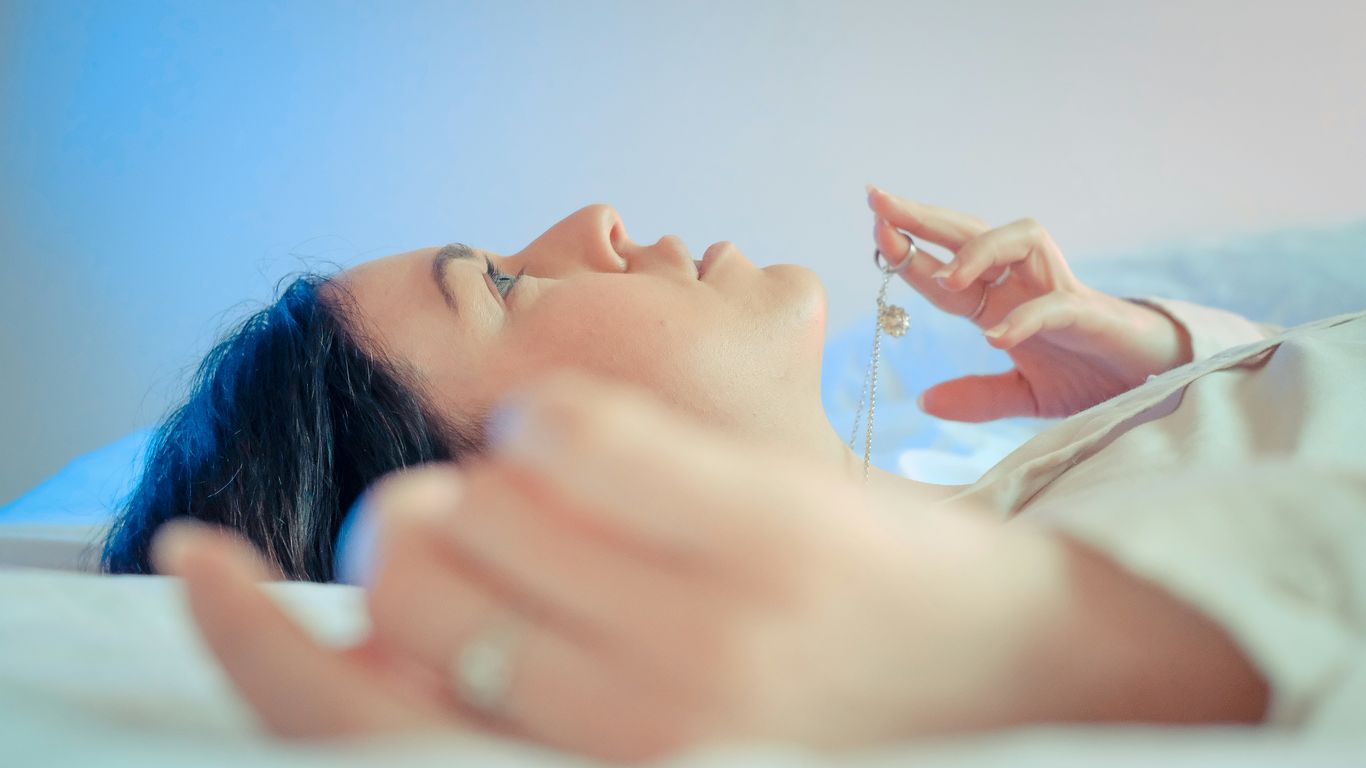 woman lying on bed with her hand on her face