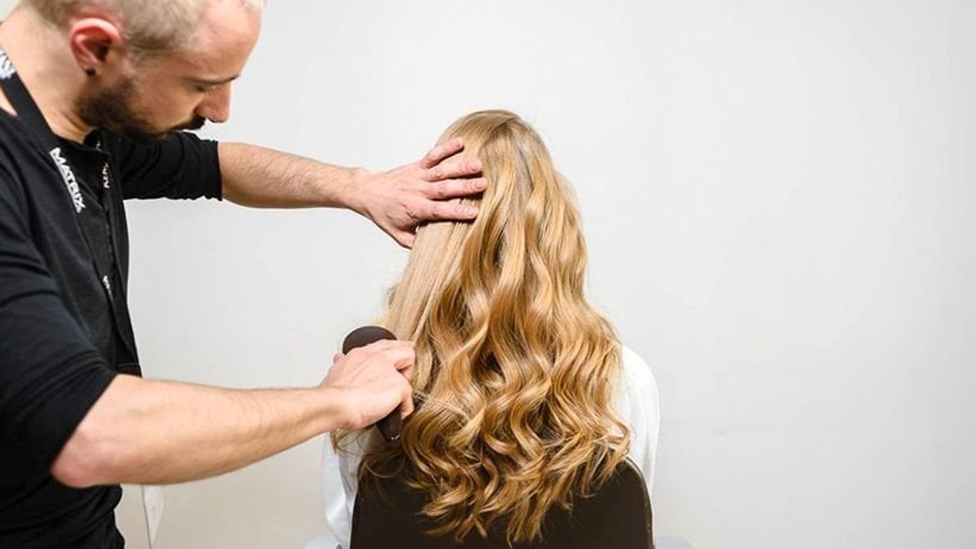 Hair stylist examining client's hair in a salon setting.