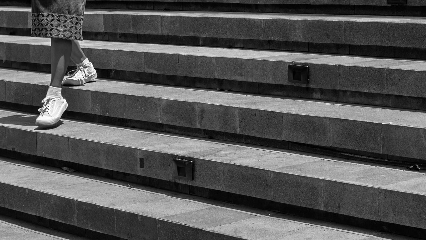 Person walking down stone stairs in black and white