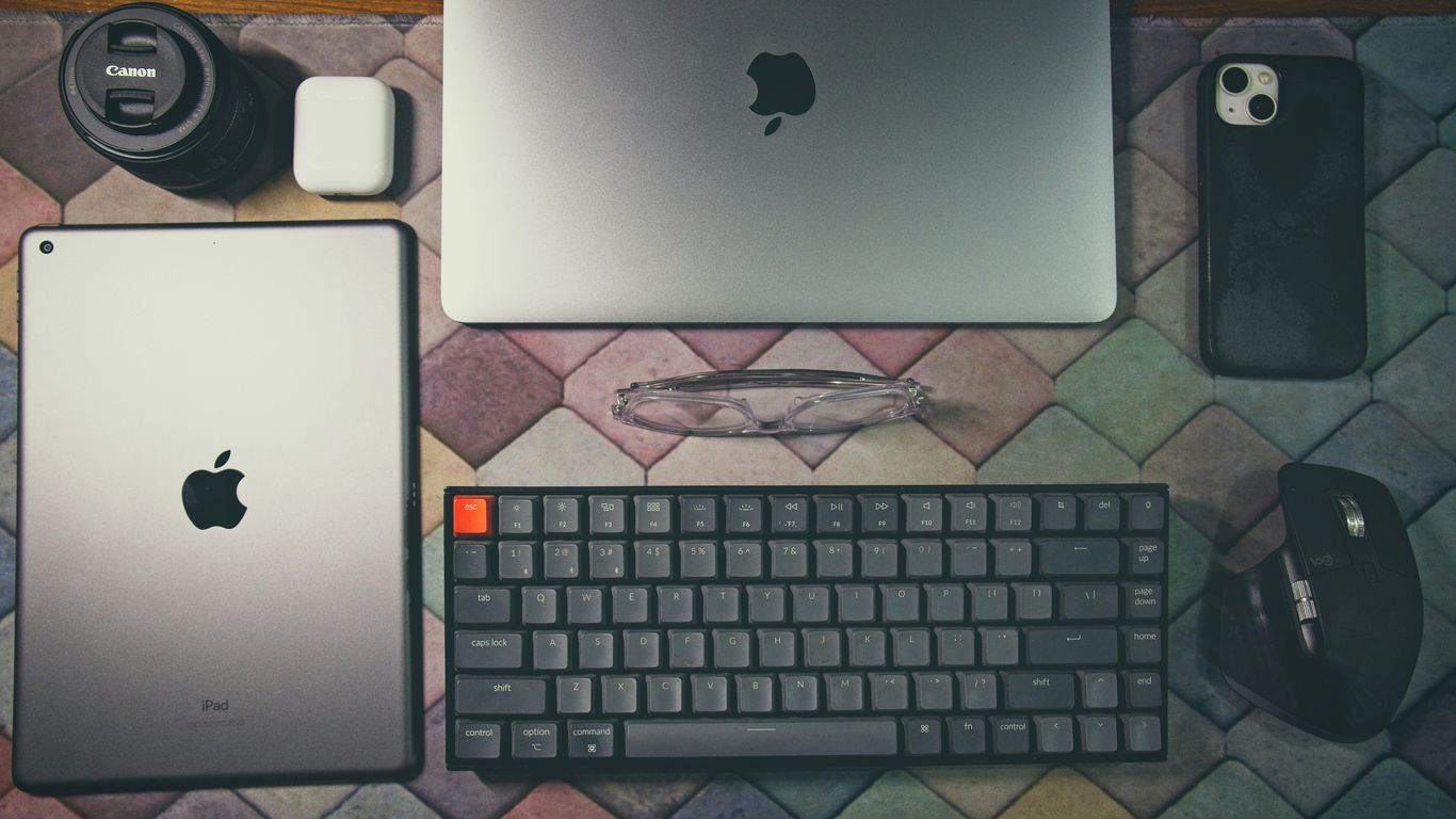 a laptop, keyboard, mouse, and other electronics on a table