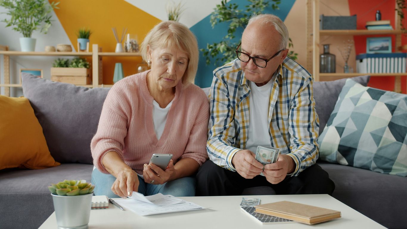 Elderly couple looking at bills and phone