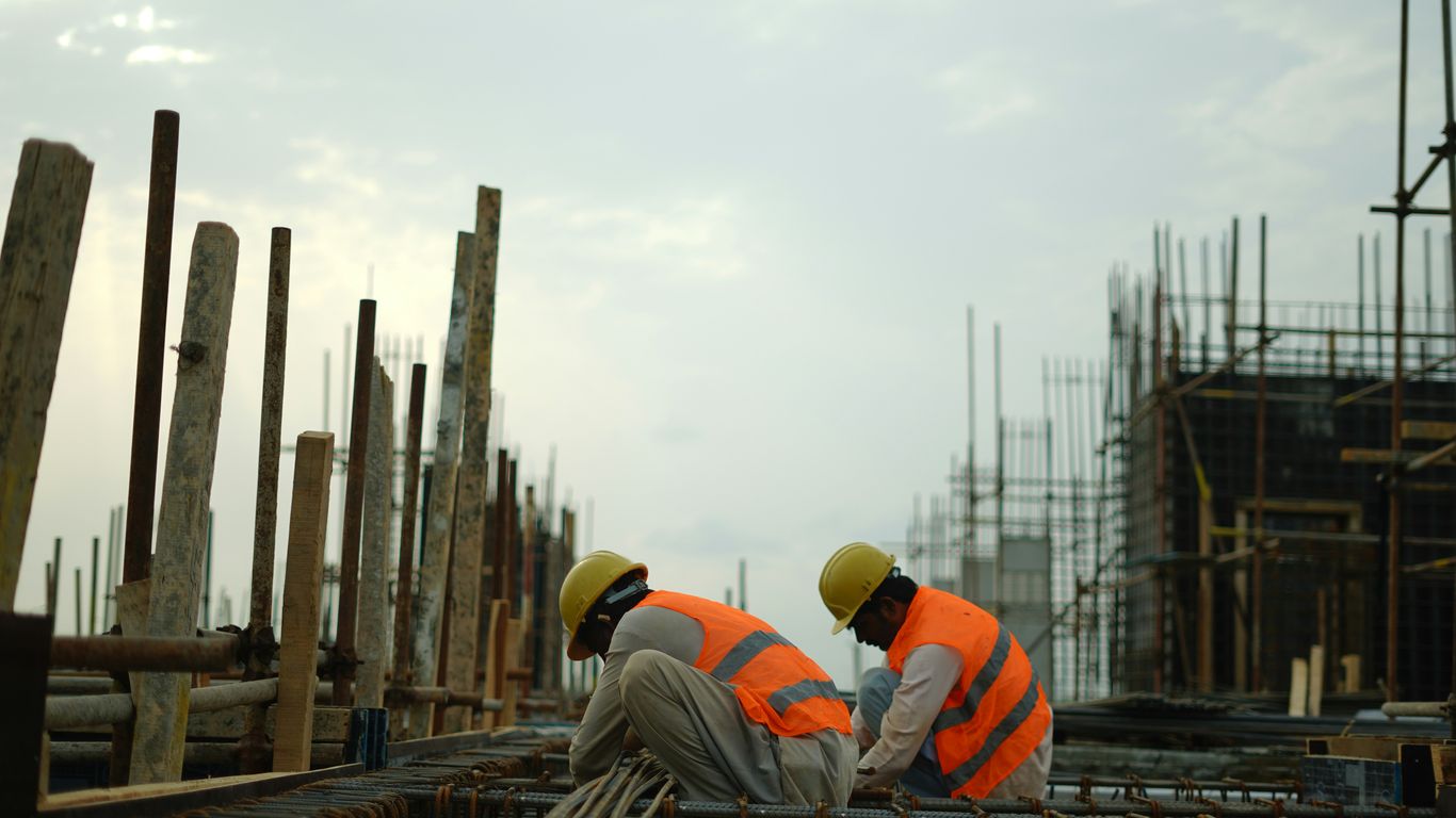 Construction workers in hard hats and safety vests on site.