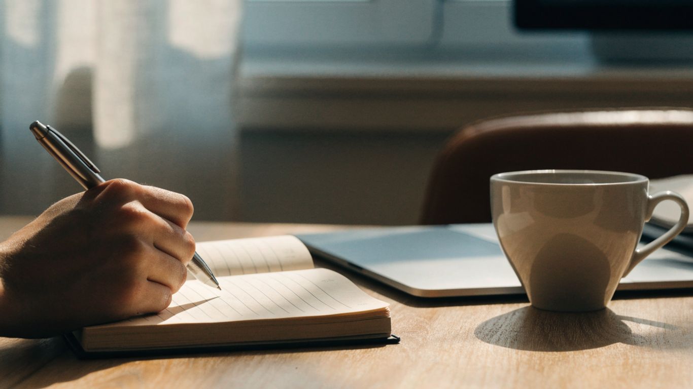 Enter to win cash. A notebook and laptop beside a cup of coffee