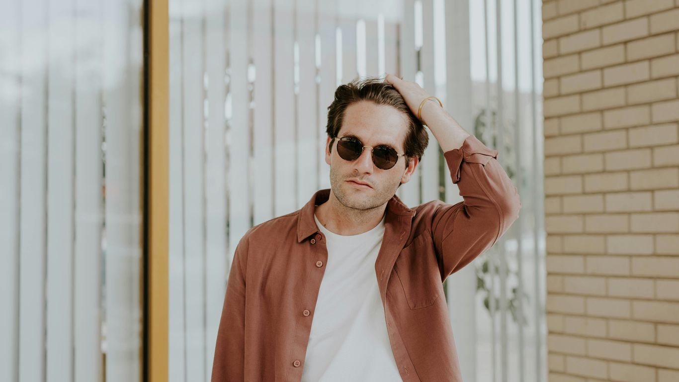 man in brown jacket near window blinds