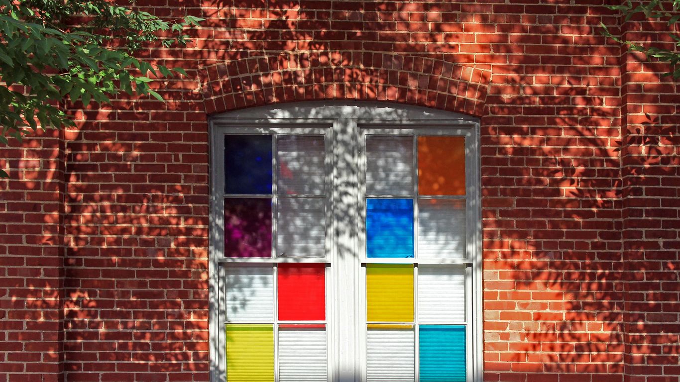 A window displays colorful stained glass on brick.