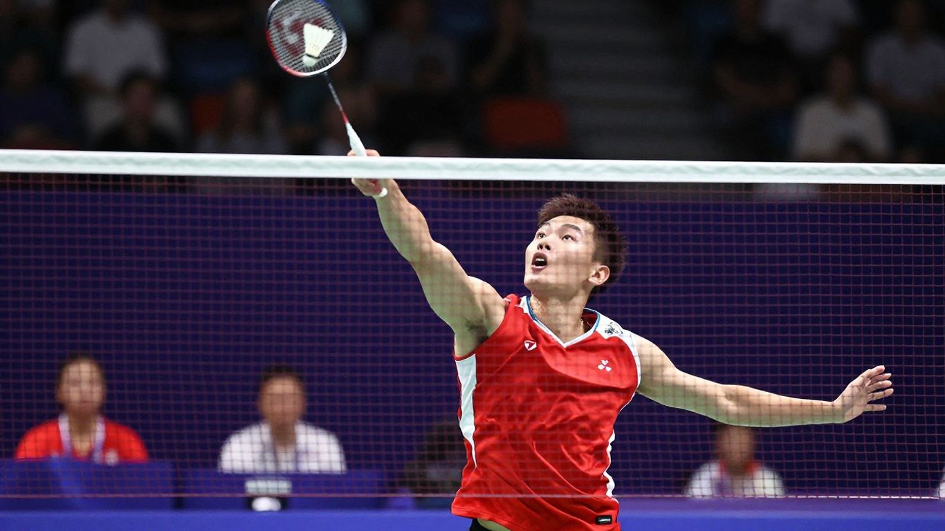 Badminton player smashing shuttlecock over the net.