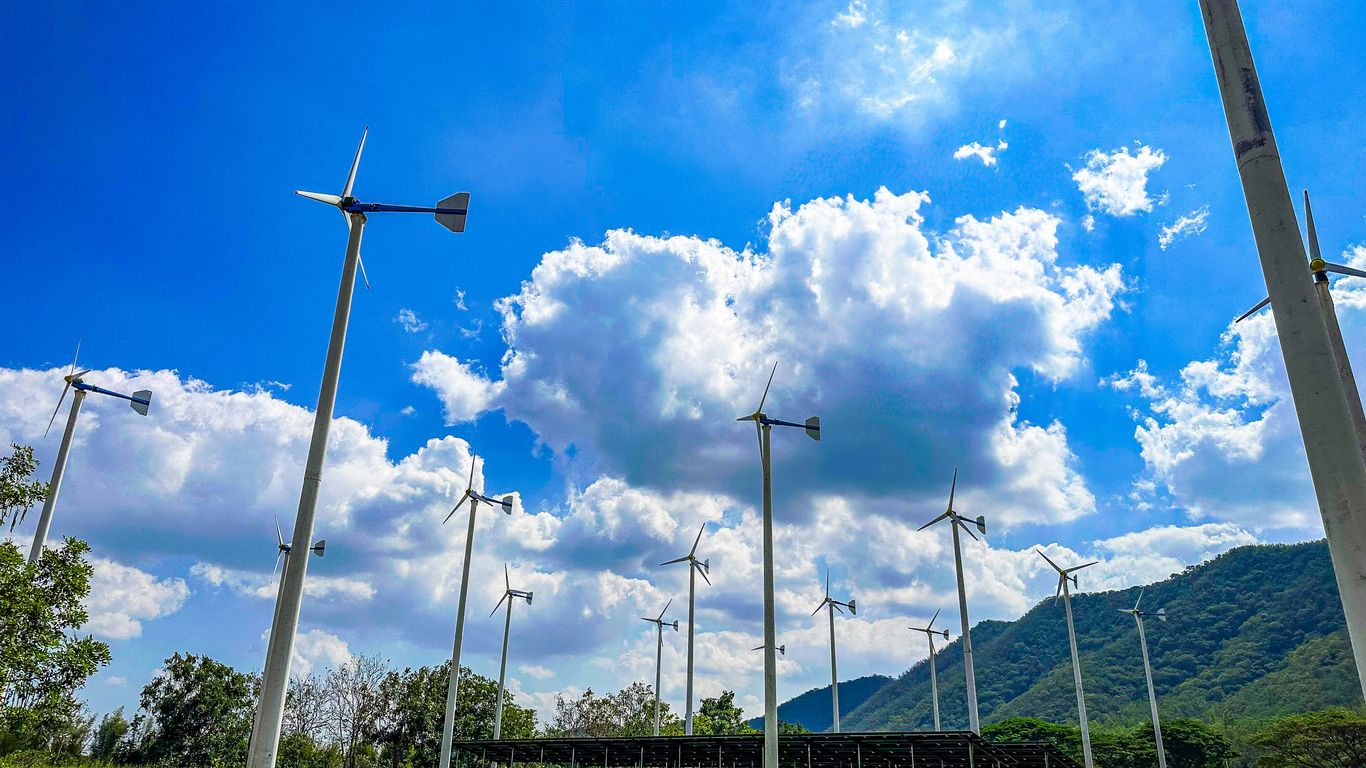 Wind turbines stand tall under a bright blue sky.