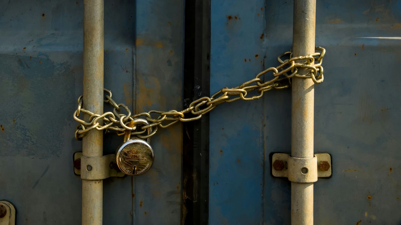 A rusty padlock and chain securing blue doors