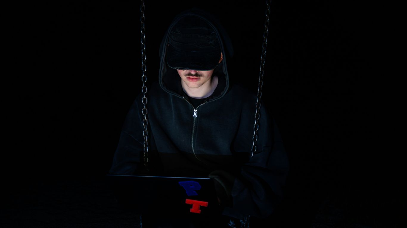 A figure is using a laptop in the dark.