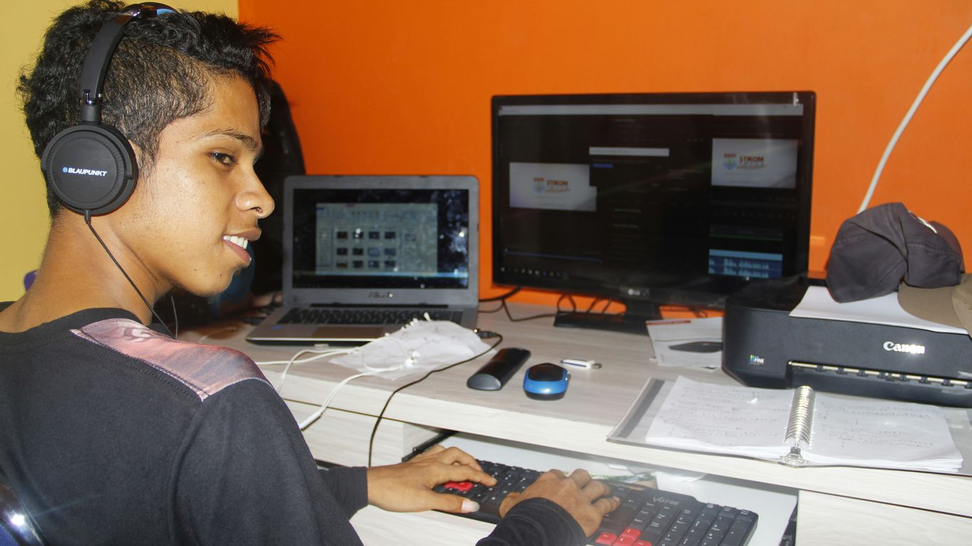 a young man sitting at a desk with headphones on