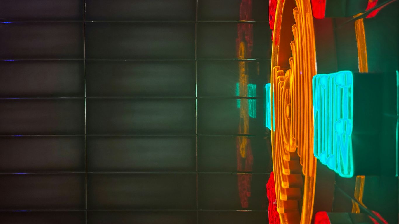 Neon lights reflect on a dark textured wall