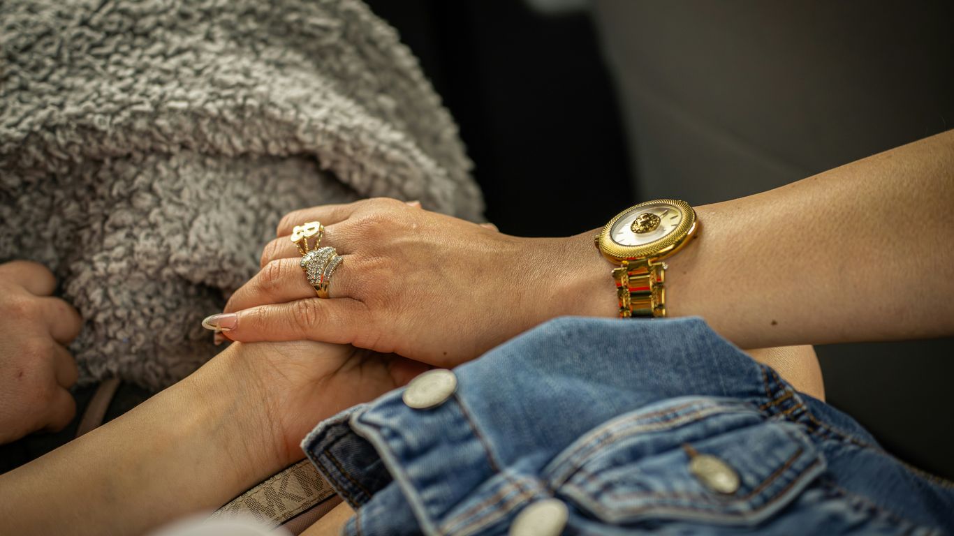 Two hands holding each other with a watch.