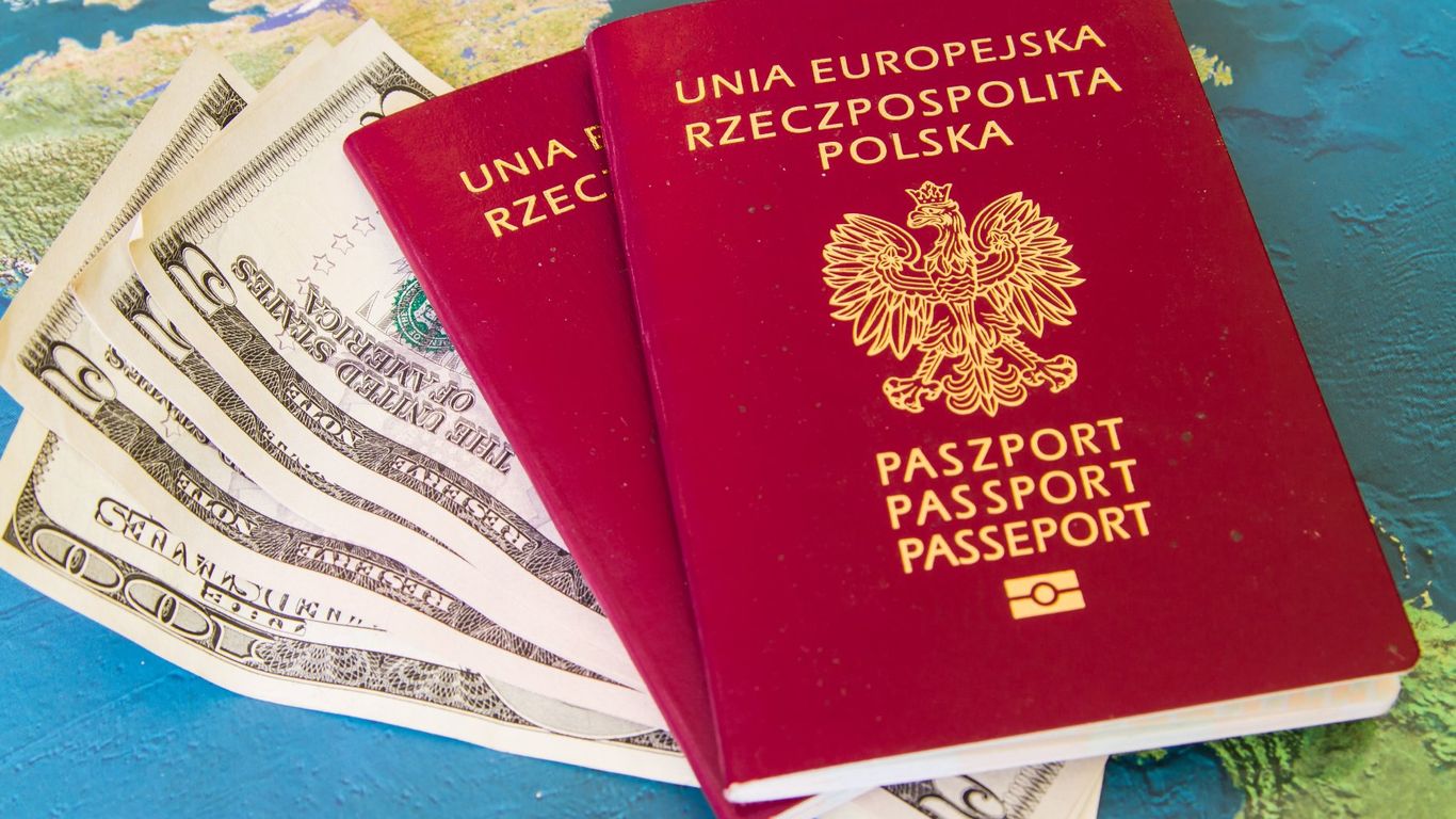 Two Polish passports and US dollars on a world map.