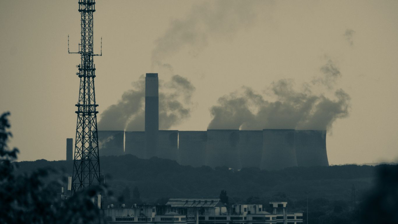 smoke billows from the stacks of industrial buildings