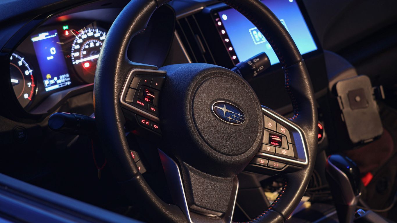A subaru car steering wheel and dashboard is shown.