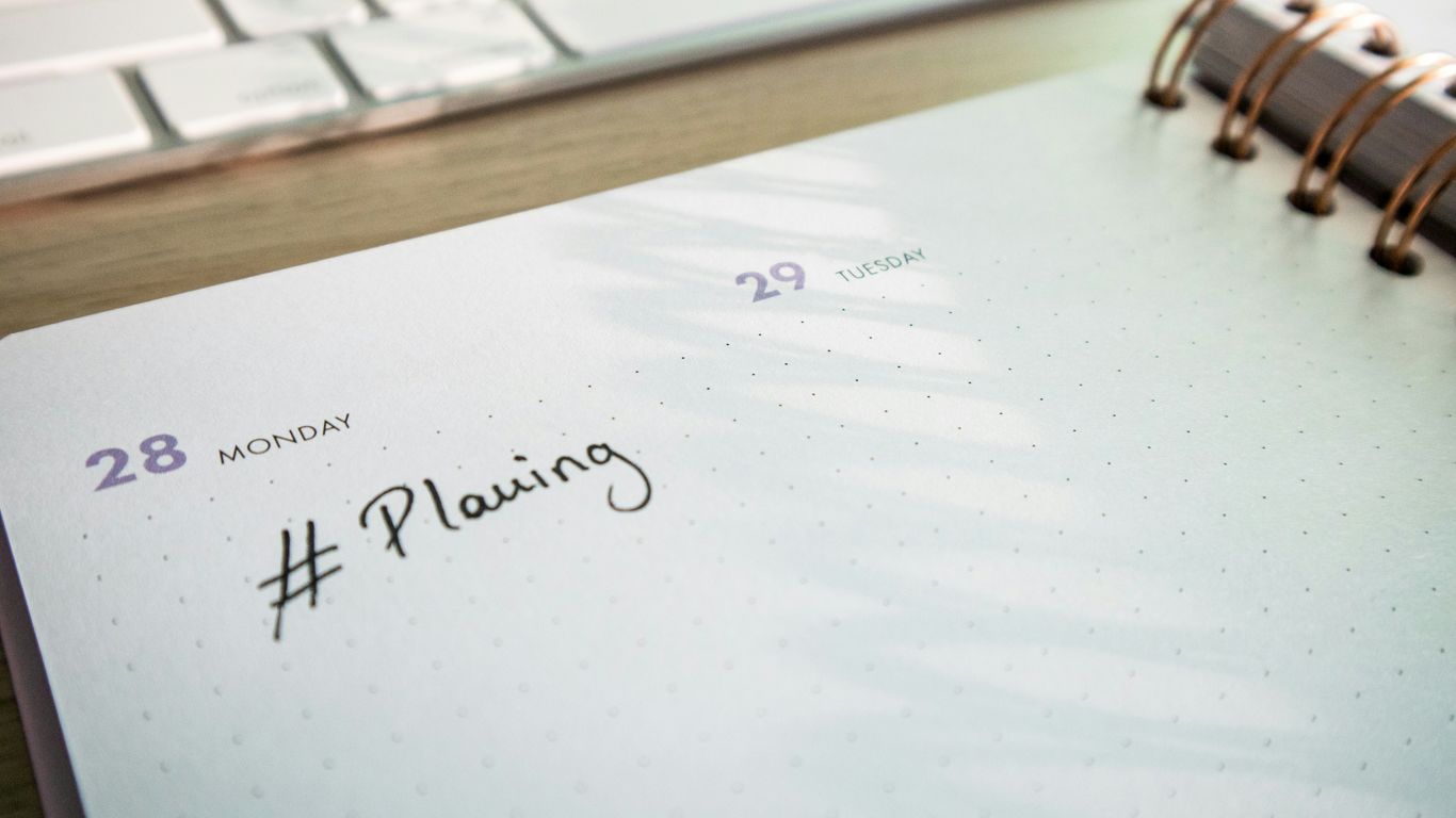 a notepad with a planner and a keyboard in the background
