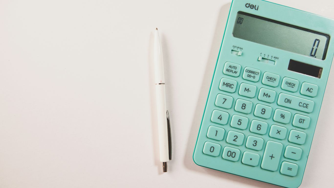 A teal calculator and white pen on a white surface.