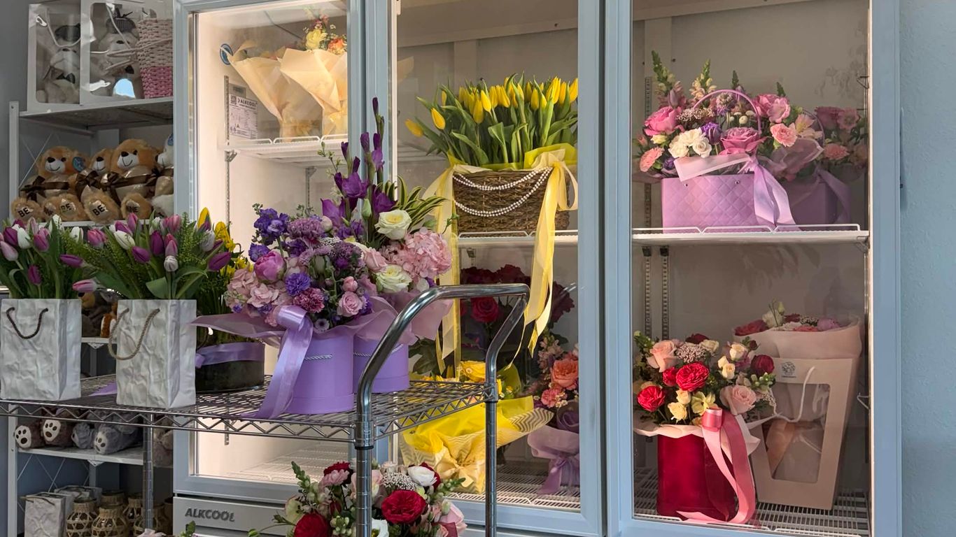 A refrigerated display case filled with various fresh flower arrangements.