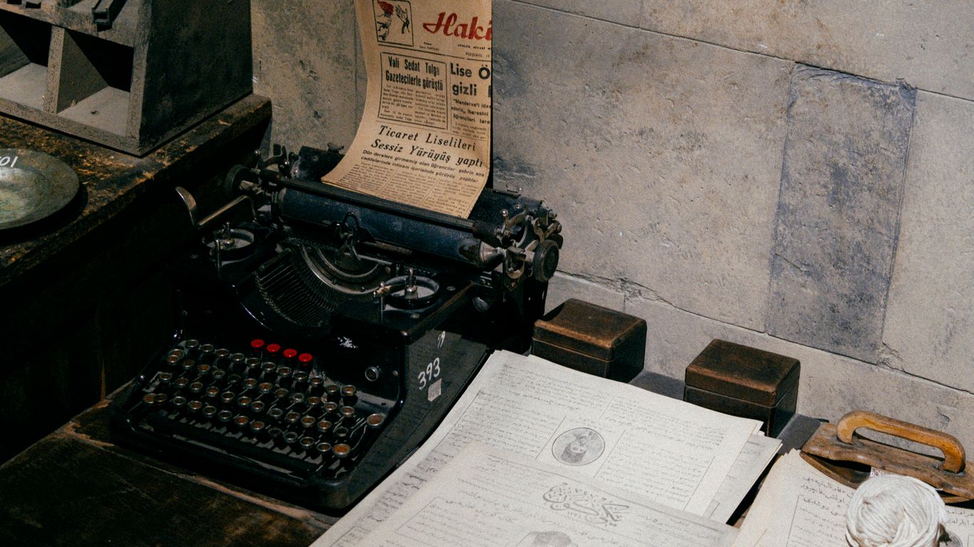 black typewriter beside white printer paper