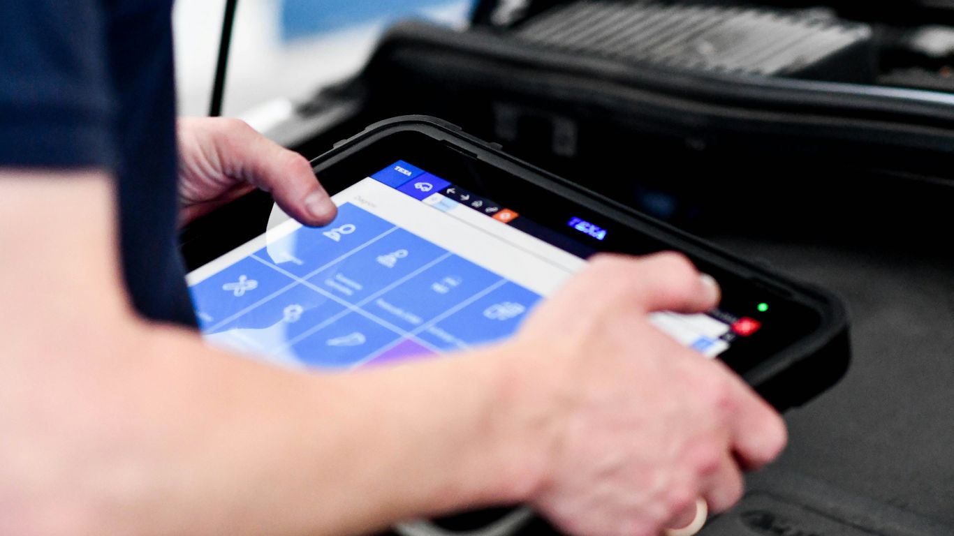 Technician diagnosing vehicle electronics onsite