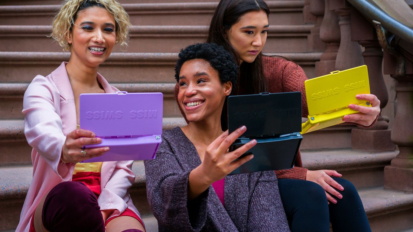 woman in purple sweater holding ipad beside woman in black sweater