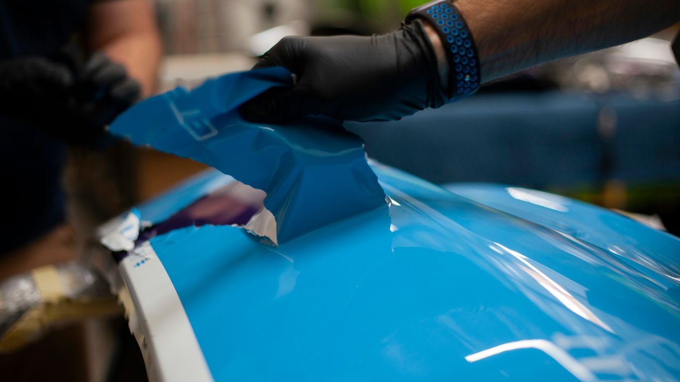 a person wearing gloves and gloves is painting a blue car