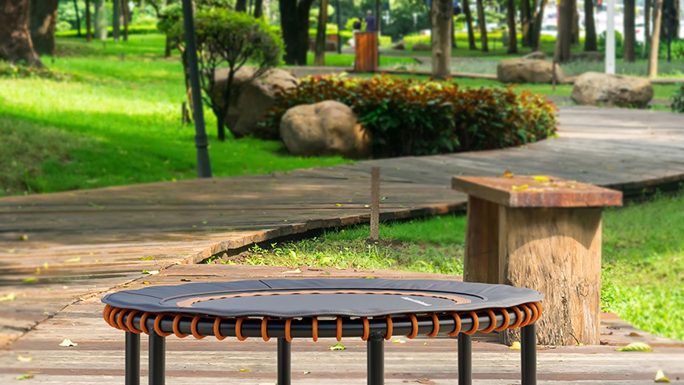 Small trampoline on wooden path in a green park setting.