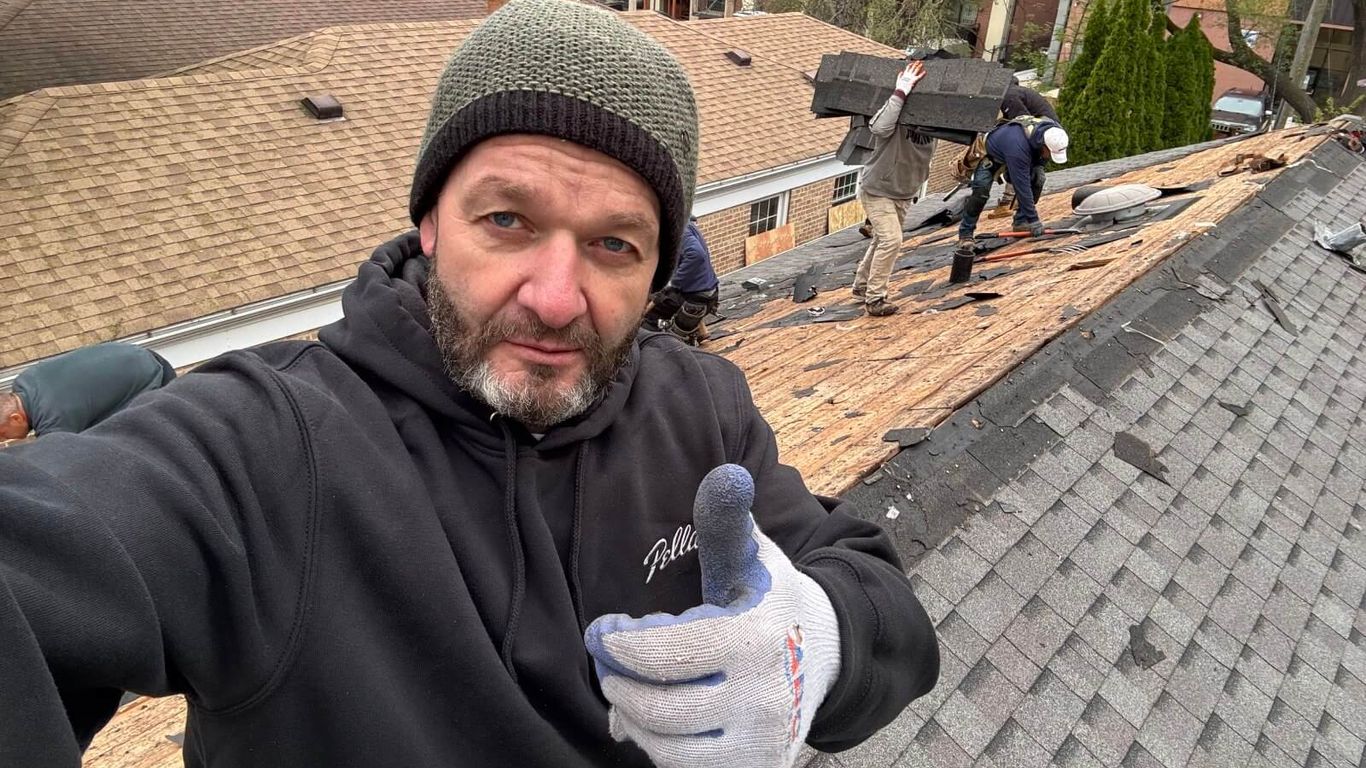 A person on a rooftop gives a thumbs up while others work.