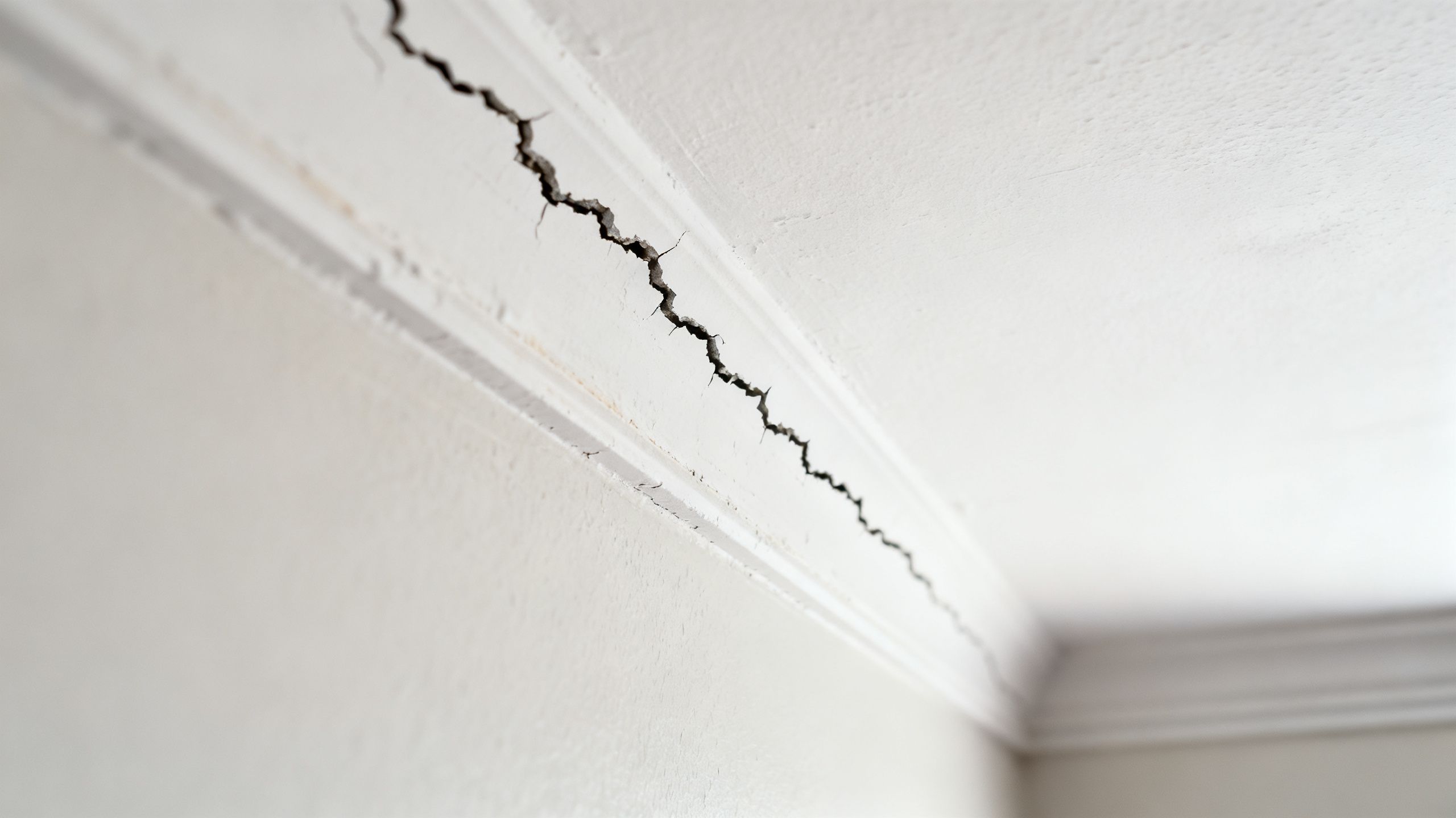 Close up of a ceiling crack running in a straight line along a plasterboard joint