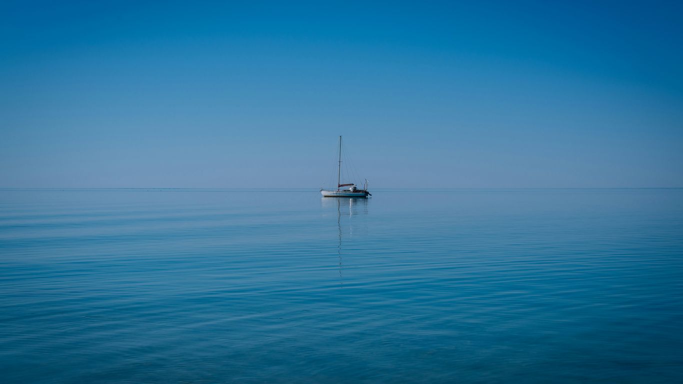 A lone sailboat on a calm, blue ocean.