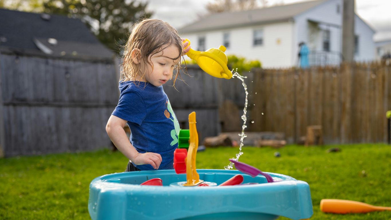 a little girl playing with a toy in a yard